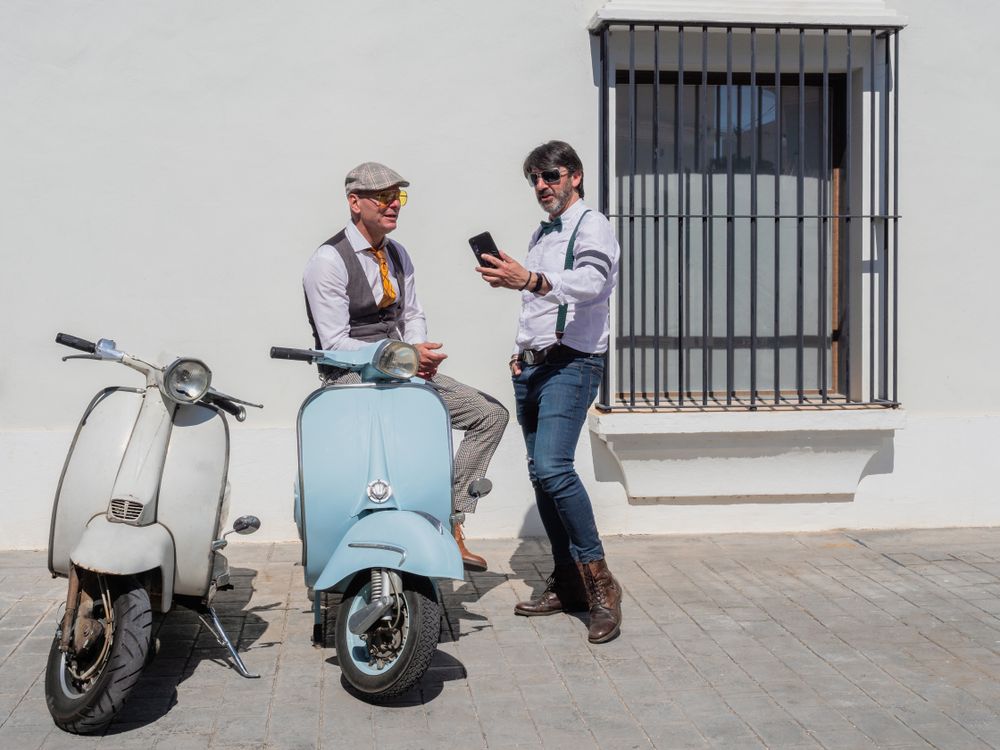 Trendy men taking a selfie vintage scooters