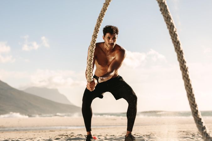 Fit male doing arm exercises with battle rope