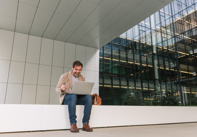 Cheerful businessman using laptop on street