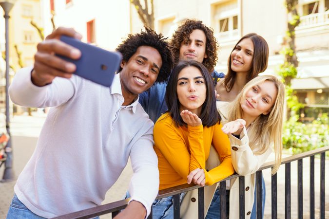 Man holding camera taking selfie with his group of friends