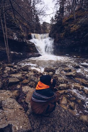 Woman gazing at fast mountain river in forest