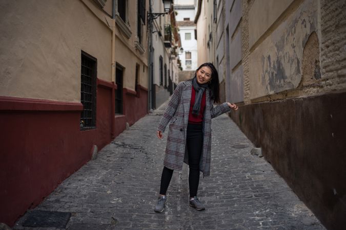 Joyful Asian resting female hiking on old rocked narrow street