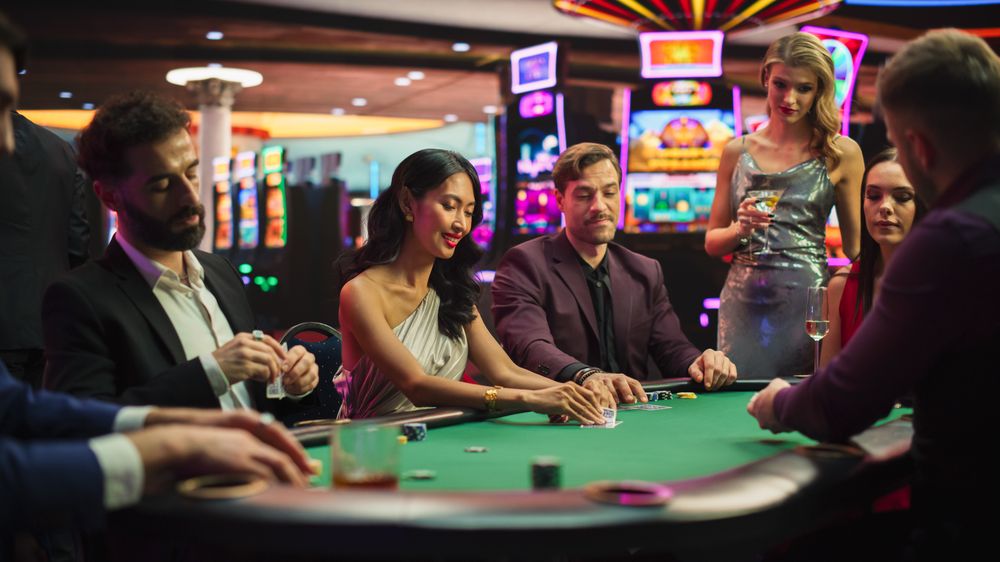 Group of Diverse Poker Players Sitting at a Table as the Croupier Deals the Playing Cards in a Modern Casino.