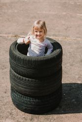 Little girl standing in stack of tires