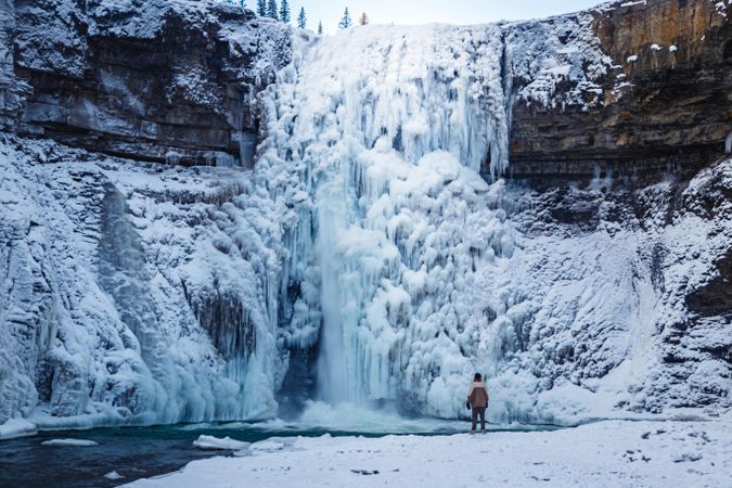 Person standing beside frozen waterfalls