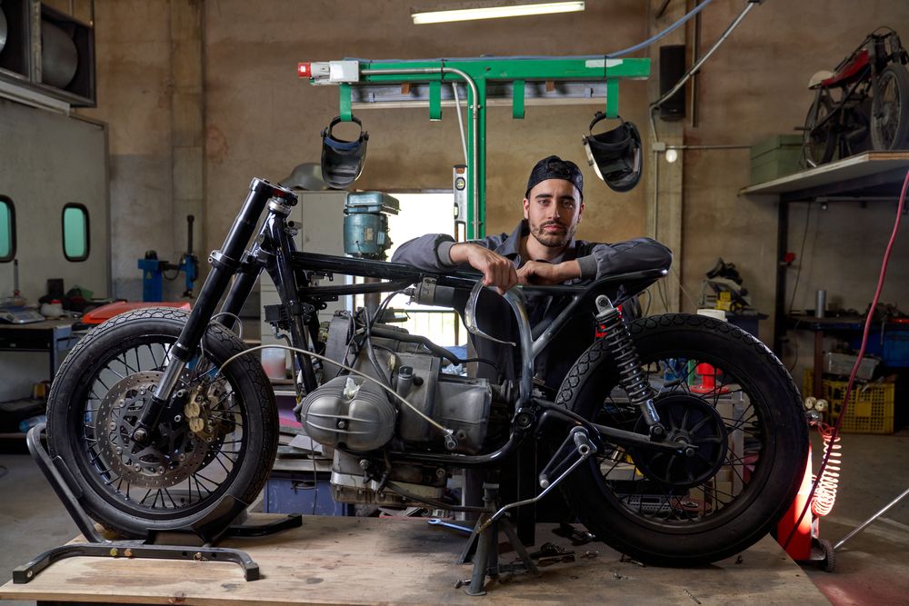 Young technician fixing motorcycle in garage