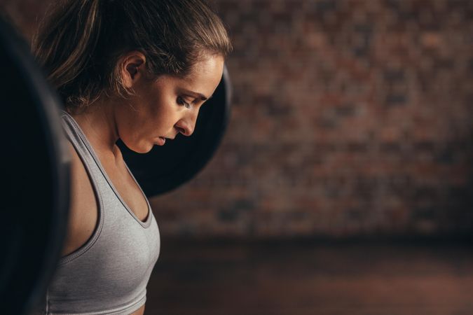Determined woman at gym exercising with heavy weights