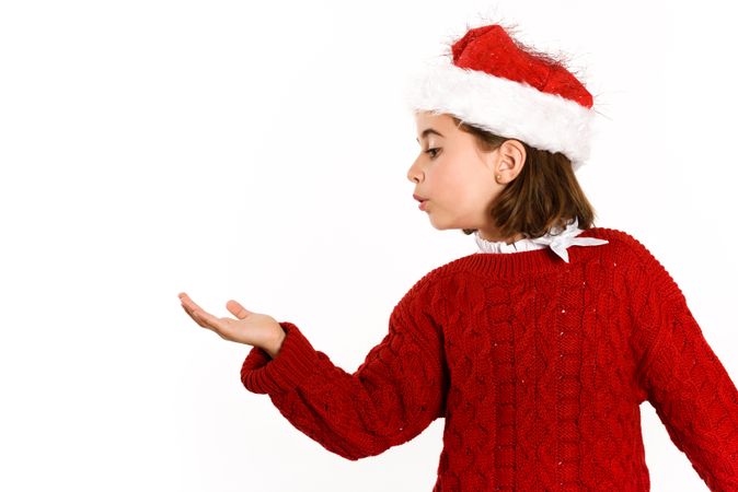 Girl in Christmas outfit with hand up to copy space