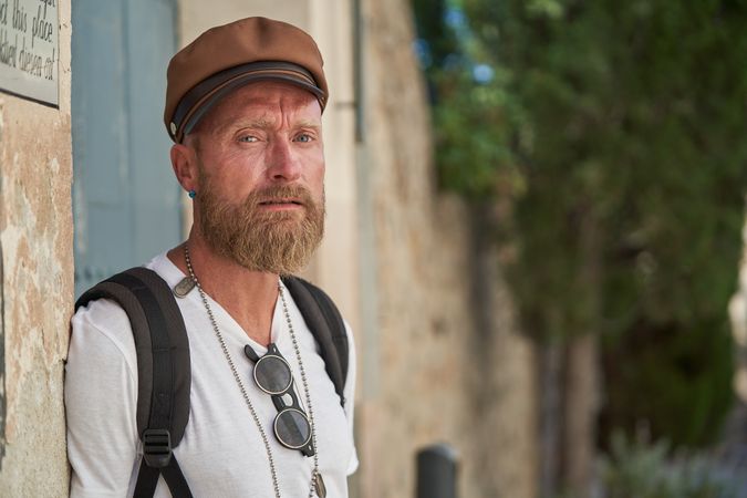 Mature bearded man in cap standing on street