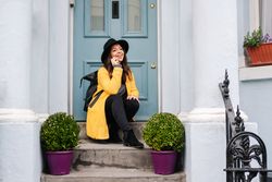 Happy female talking on smartphone on doorstep