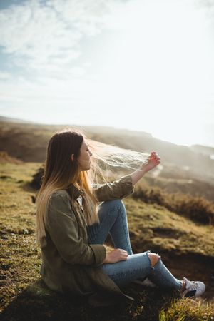 Pensive woman sitting on grass and looking at seascape