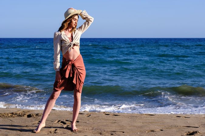 A fashion model with a hat at the beach before sunset