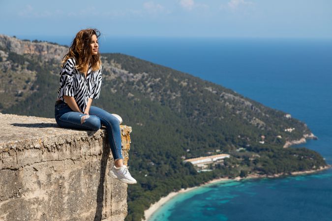 Woman sitting on concrete block near sea