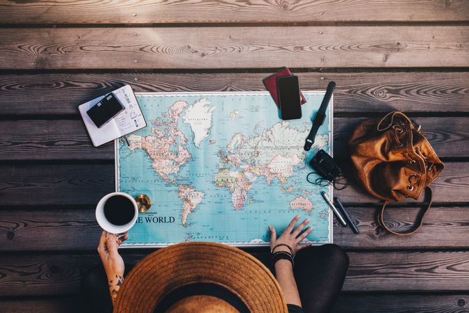Young woman planning vacation using a world map, compass and other travel accessories