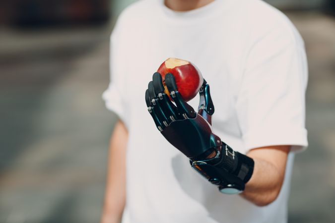 Cropped image of man with prosthetic hand holding a red apple
