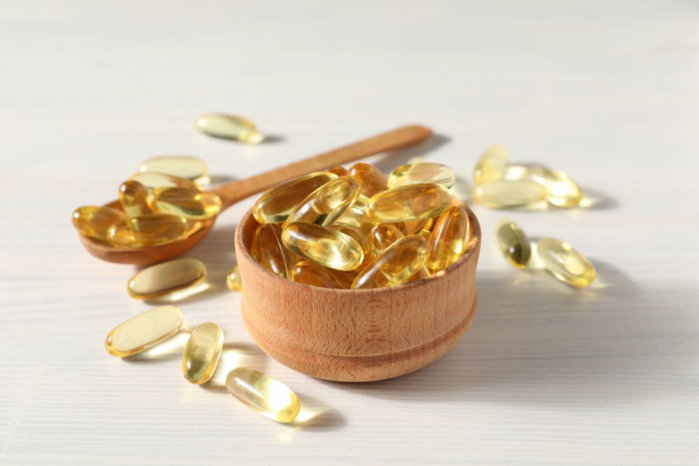 Omega pills in a wooden bowl on a plain background