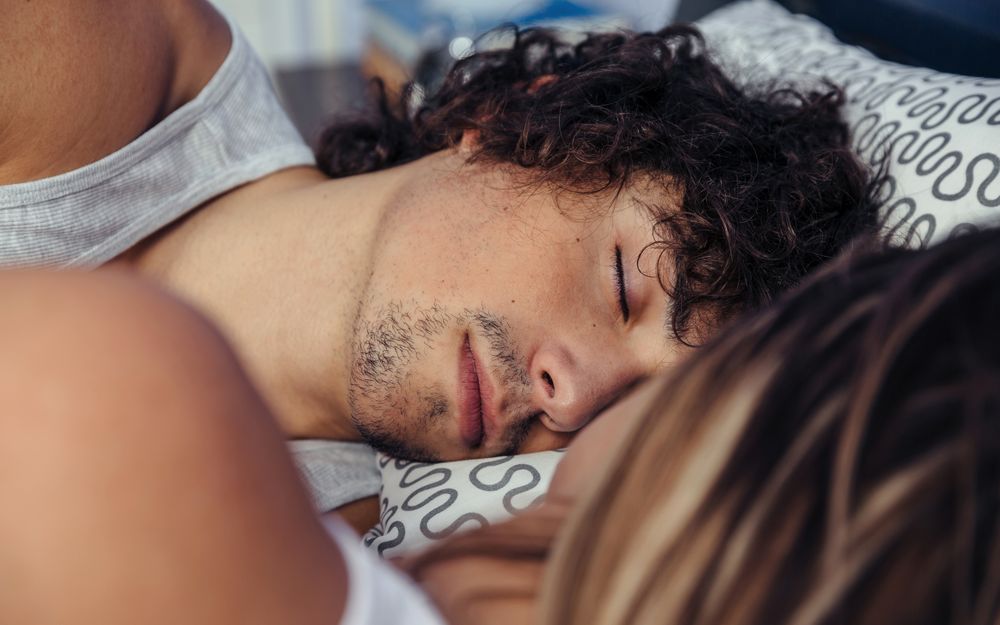 Couple sleeping in bed facing each other
