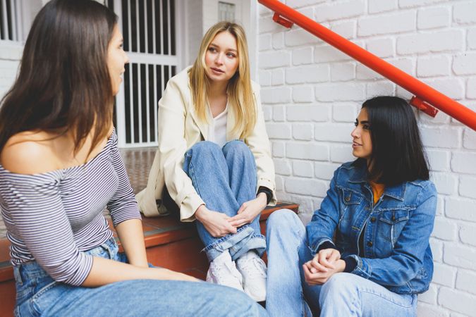 Three women having a conversation on outdoor brick steps