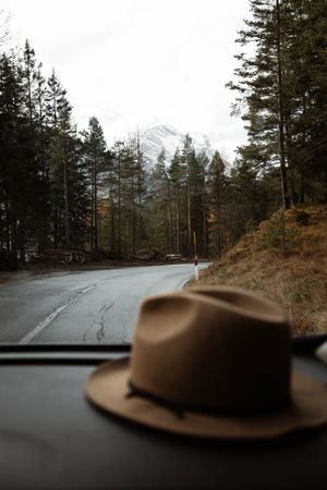 Hat inside a car at lonely highway amid mountains