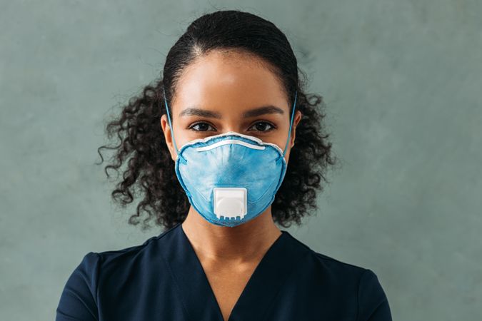 Black female medical professional in protective face mask on grey background