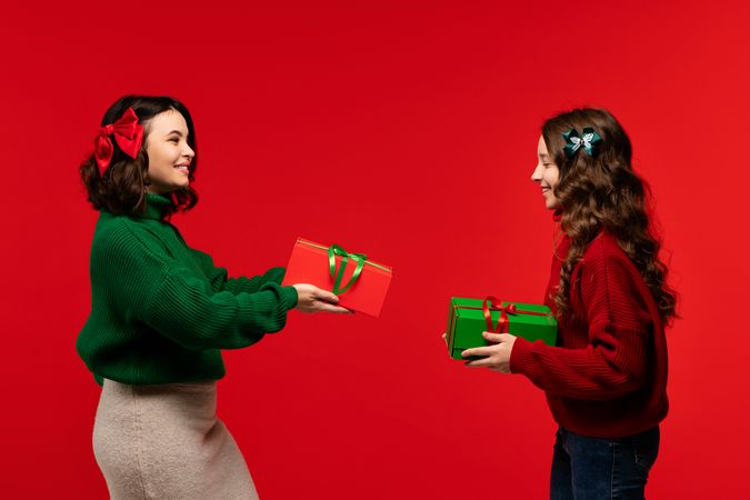 Mum and teenage daughter happily exchange holiday gifts in studio