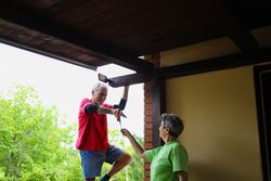 Woman giving a screwdriver to her husband while he is installing the new light on their home.