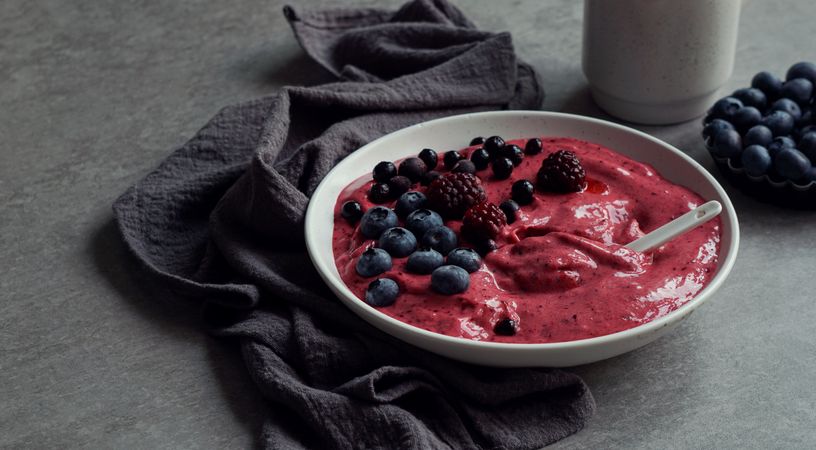 Smoothy of fresh bog blueberries and raspberries in bowl near napkin