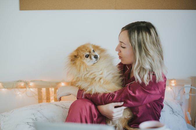 Smiling woman sitting in bed with dog