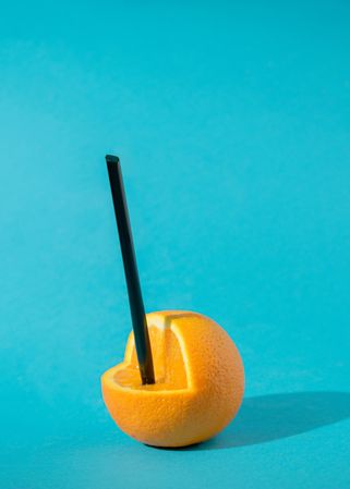 Orange with slice taken out with straw