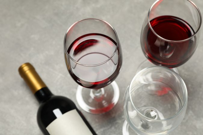 Flat lay composition with bottle and glasses of wine on grey background, copy space