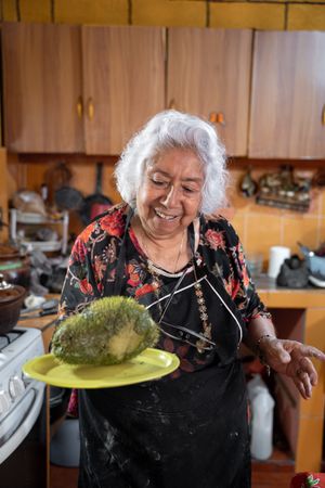 Portrait of older woman smiling showing a fresh cooked chayote