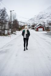 Solitary woman on empty street in small town against snowy hillside