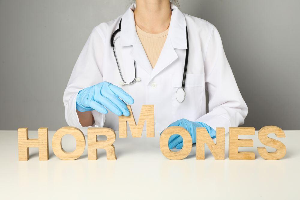 The word hormones in human hands, on a light background.