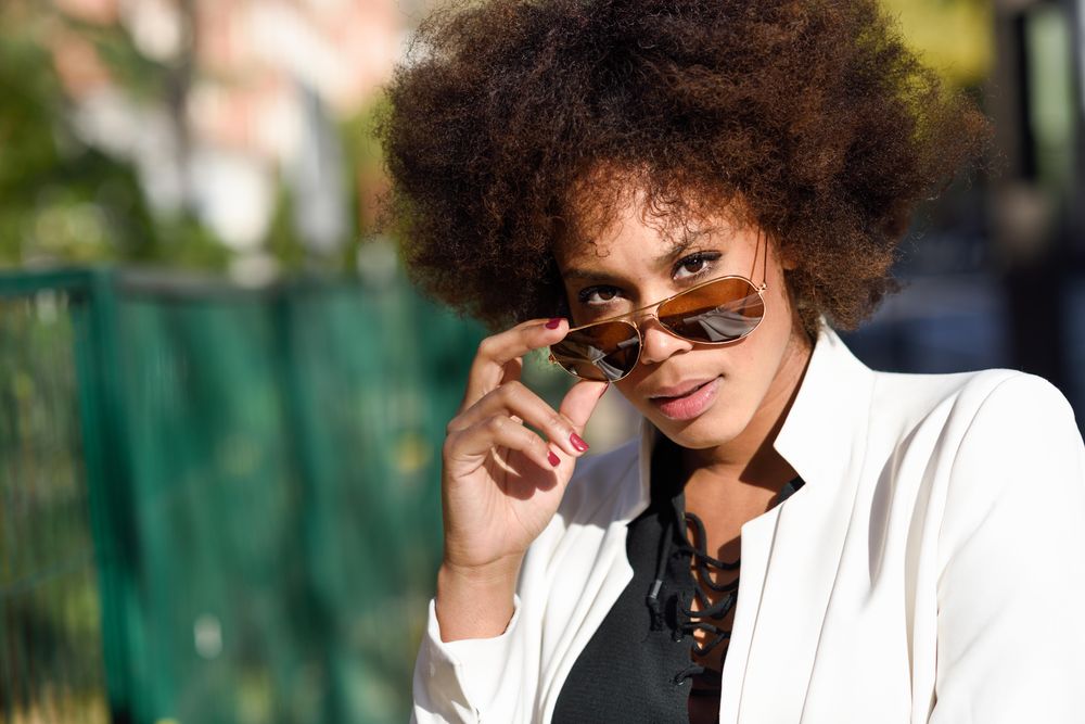 Serious stylish female looking up from aviators sunglasses on street