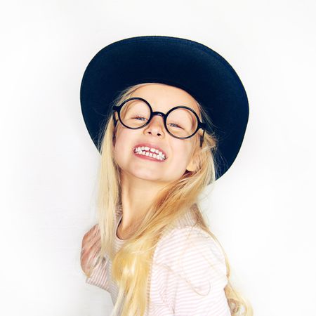 Blonde girl smiling wearing hat and glasses