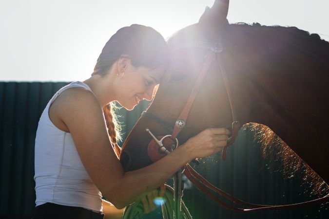Woman taking care of his brown horse in an equestrian center