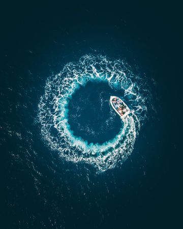 Aerial view of boat making a circular shape with water in sea