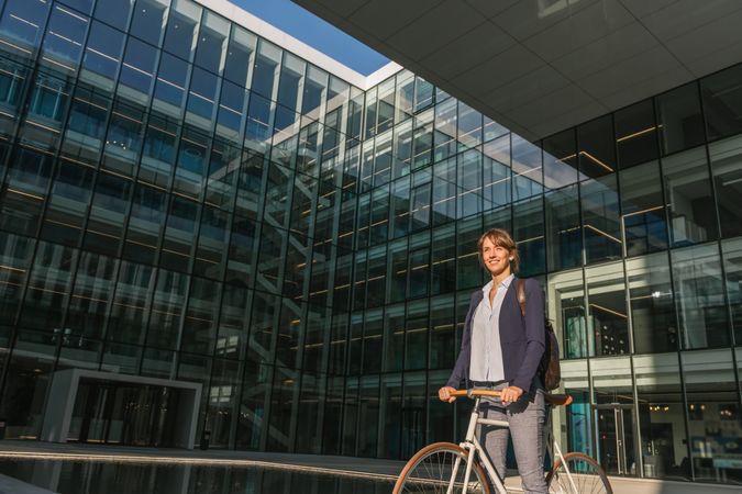 Cheerful businesswoman riding bicycle on street