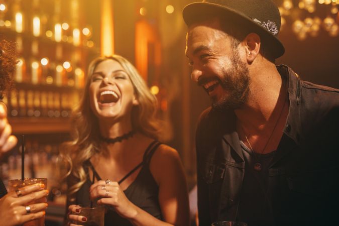 Man and woman laughing with friends in nightclub