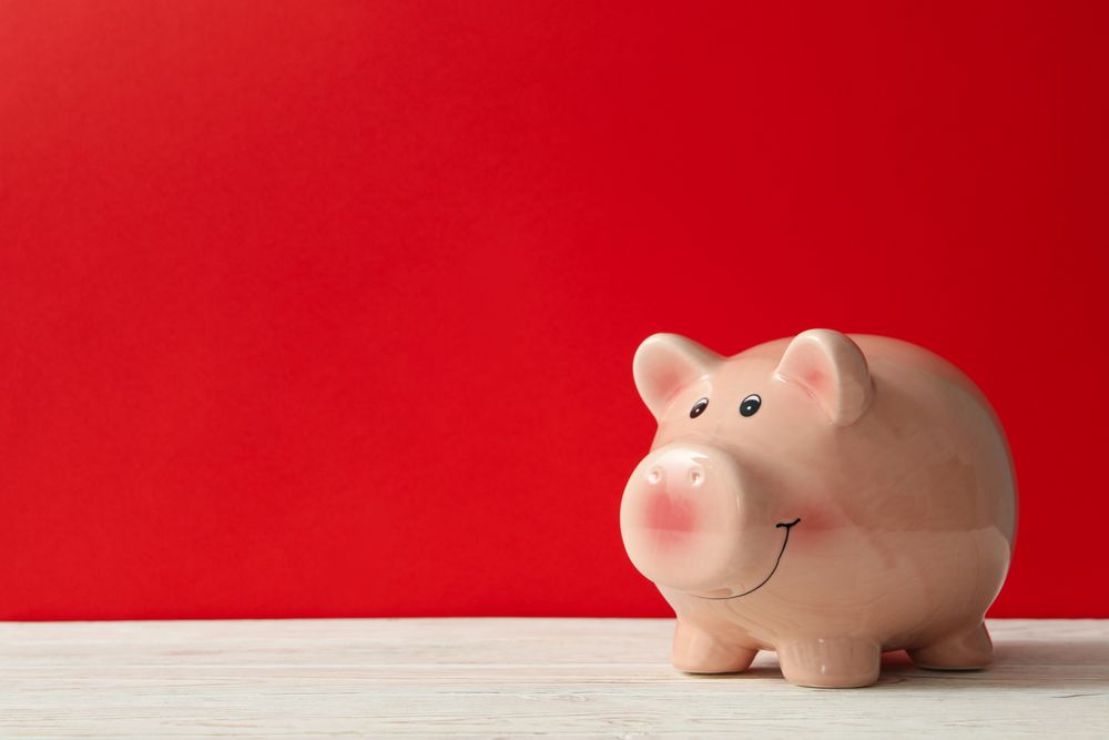 Piggy bank on red background, space for text