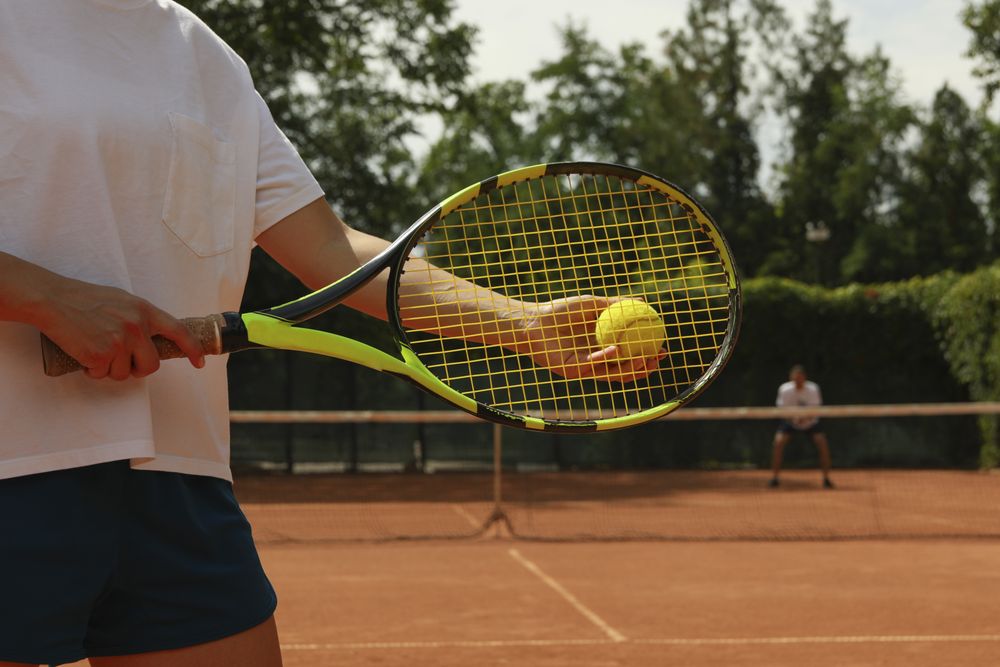 Woman hold racket and tennis ball on clay court