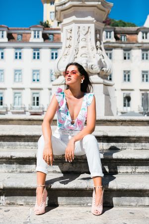stylish woman in sunglasses sitting in street stairs