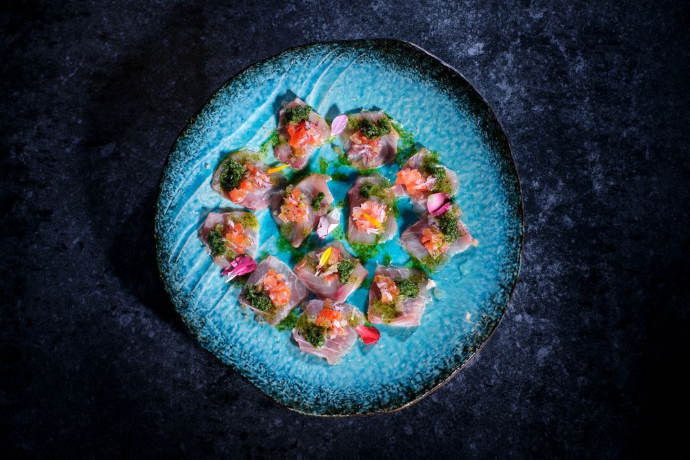 Plate with delicious fish dish on marble surface