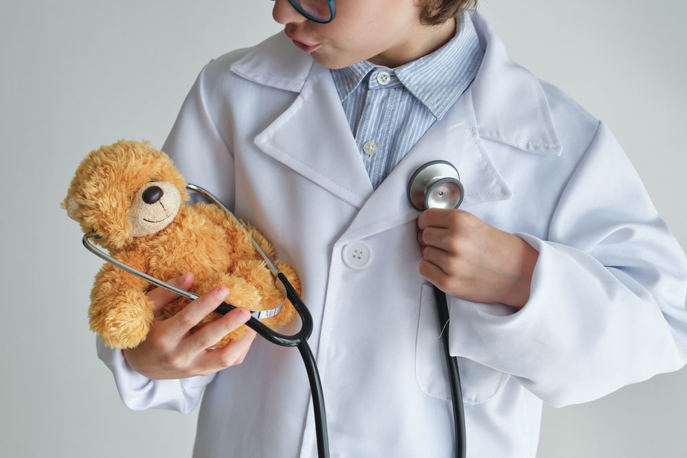 Crop boy doctor with toy bear and stethoscope
