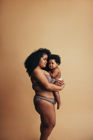 Woman with long curly hair holding her cute baby with afro