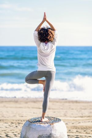 Back of Black woman doing balance exercise on the beach