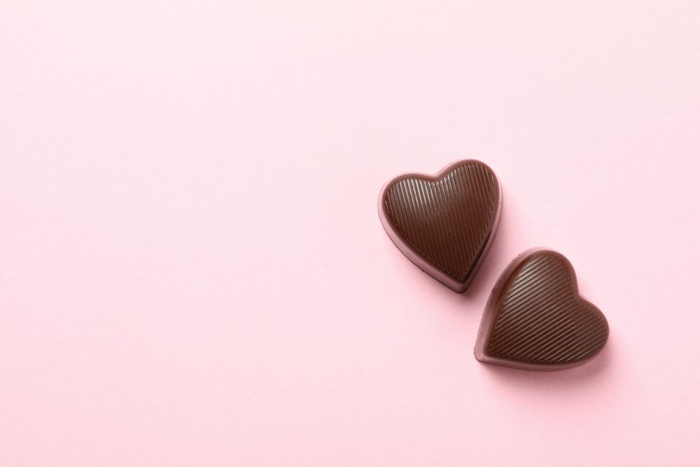 Chocolate candies in the heart form on pink background
