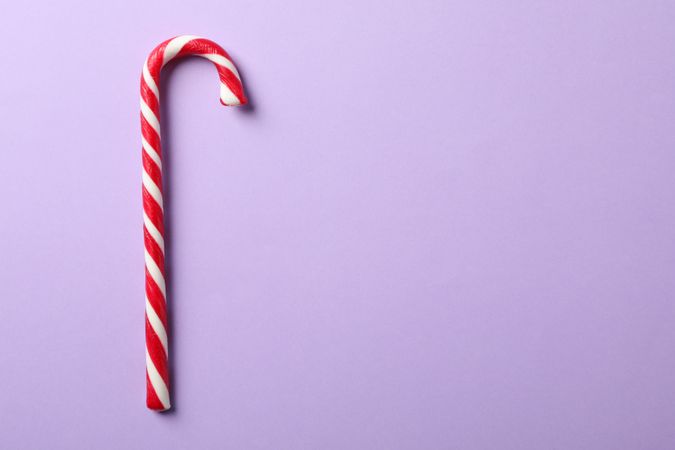 Sweet candy cane on color background, space for text