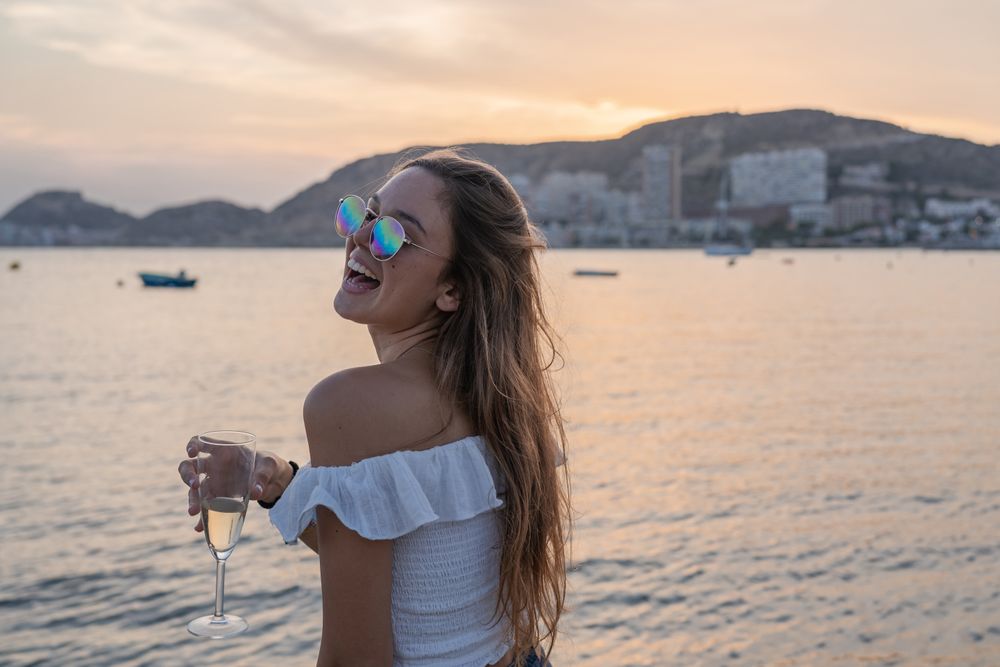 Young woman enjoying wine near sea