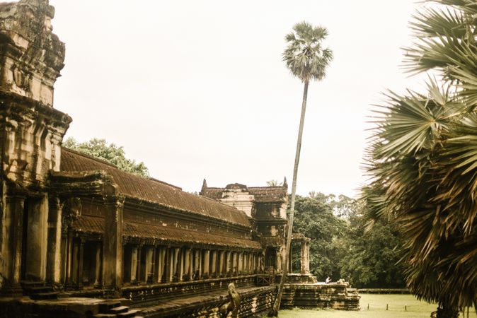 Old building between green trees in forest and cloudy sky
